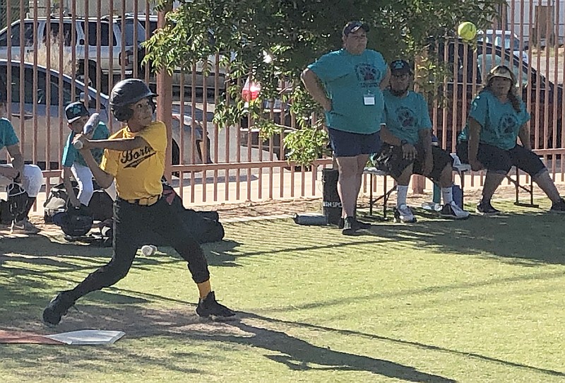 player swinging bat to hit the ball during a softball game. 