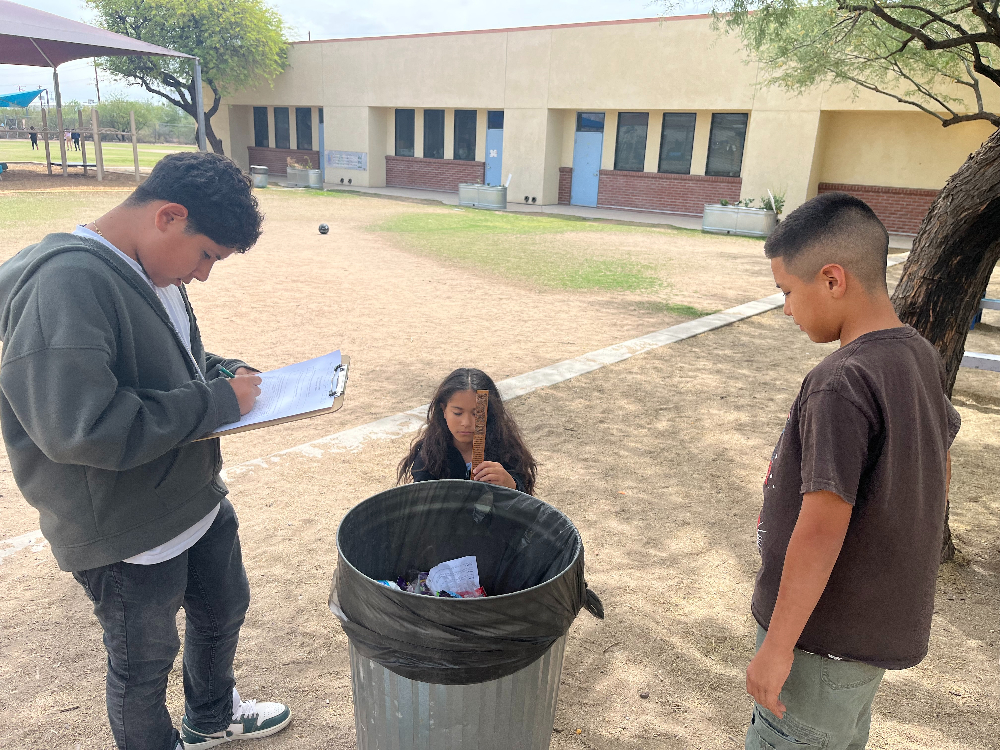 Students measure a trash can outside