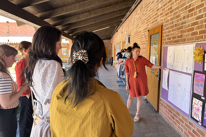 A teacher points to charts to share about Borton with visiting educators
