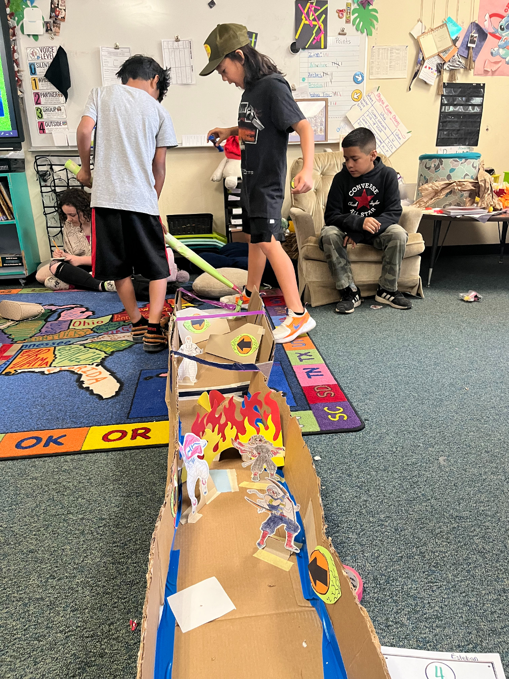 Students play mini golf on a course they made from cardboard