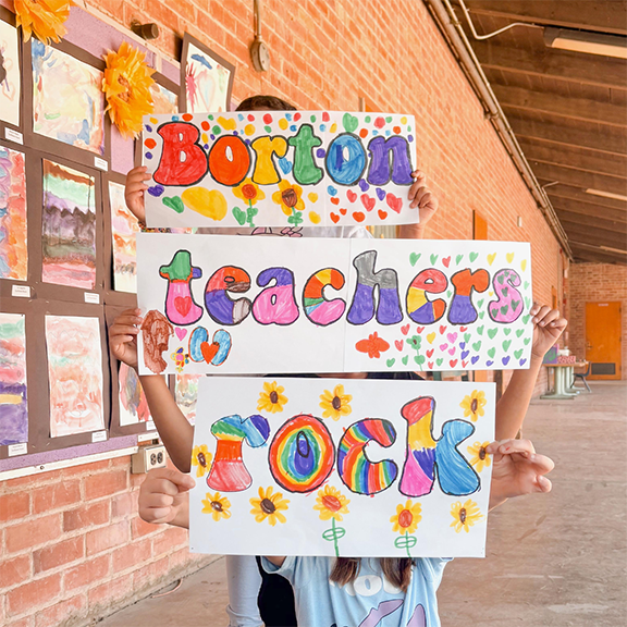 Students hold up colorful signs reading Borton teachers rock