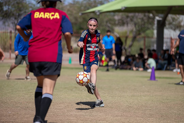 A girl in a soccer jersey kicks the ball