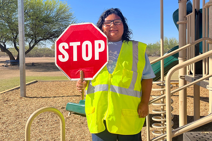 A boy dressed as a crossing guard holds a stop sign