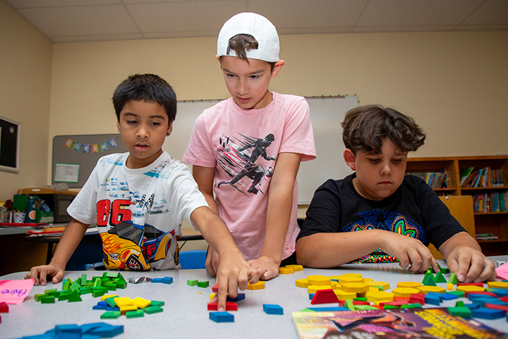 Three boys play with colorful tiles