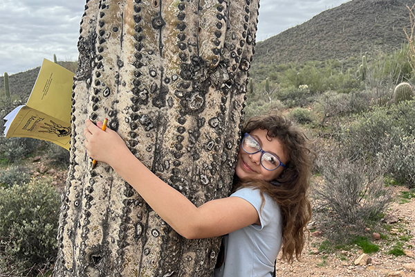 A girl hugs a saguaro cactus