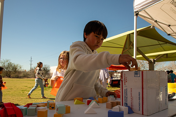 A boy stacks colorful blocks on a box