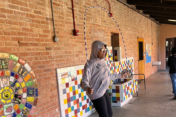 A girl wearing a hoodie jumps rope