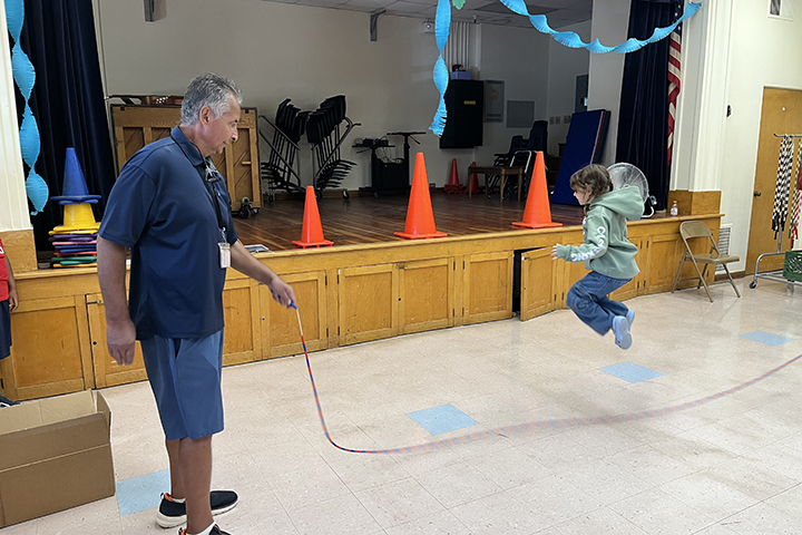 A man holds a rope while a little girl jumps over it