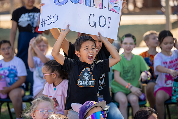 A little boy holds up a sign cheering on one of the soccer players