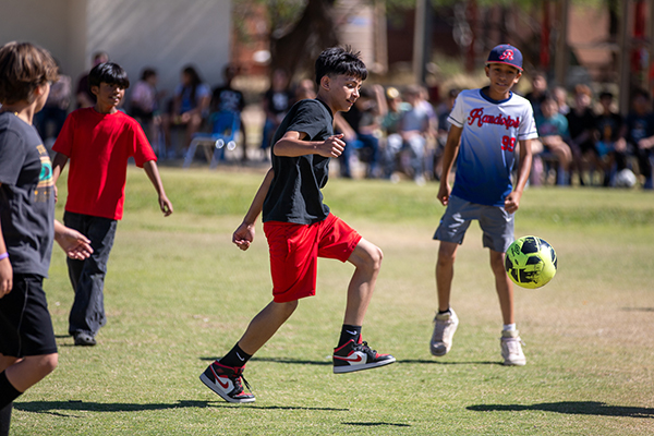 A boy kicks the soccer ball as his teammates watch