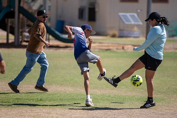 A boy and a mom go in to kick the soccer ball