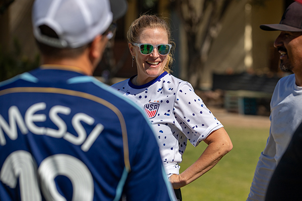 A woman in sunglasses smiles with her teammates