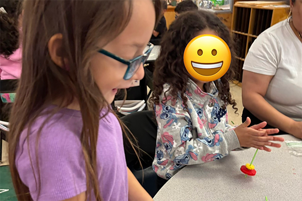 Two girls play with a spinning top
