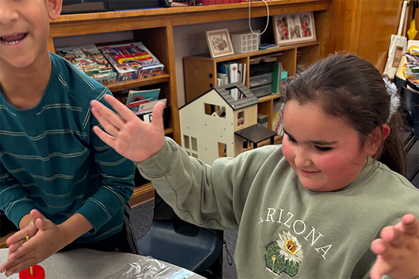 A girl puts up her hands excitedly as she watches a top spin
