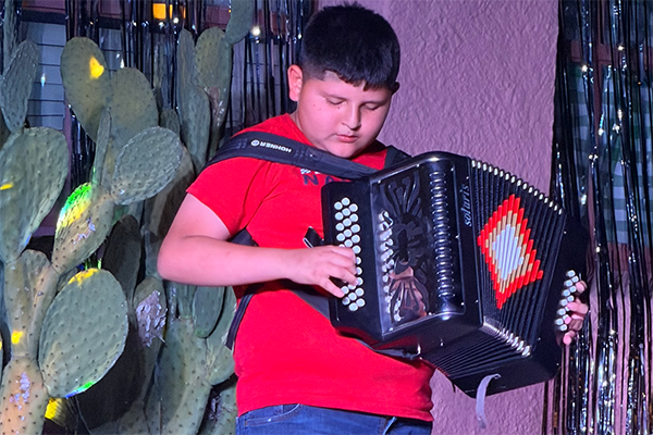 A boy in a red shirt plays accordion