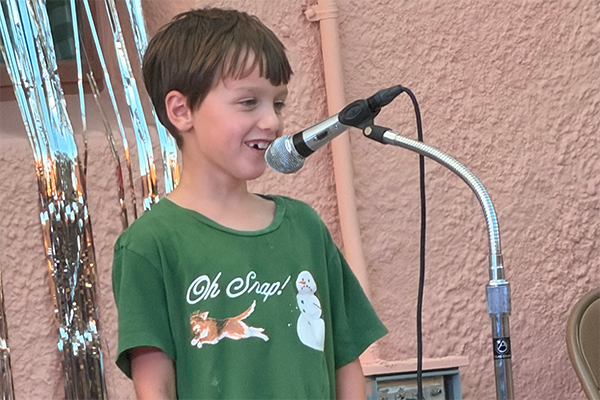A boy in a green shirt speaks into a microphone