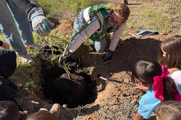 A group of students use shovels to dig a hole