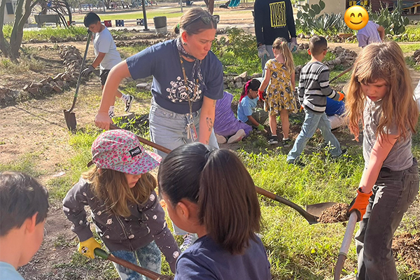 A group of students and adult volunteers dig holes to plant trees in