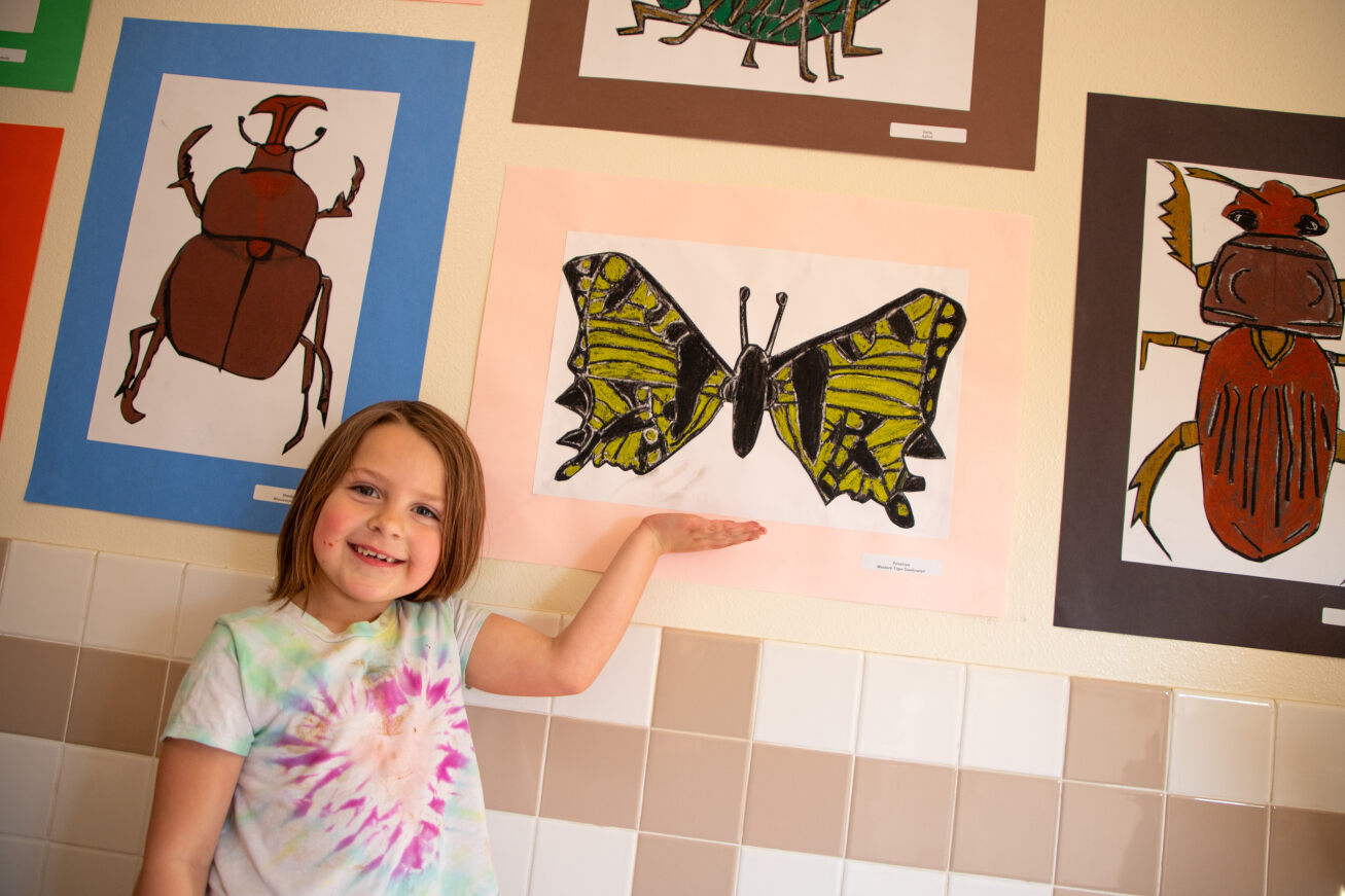 A little girl shows off her butterfly painting