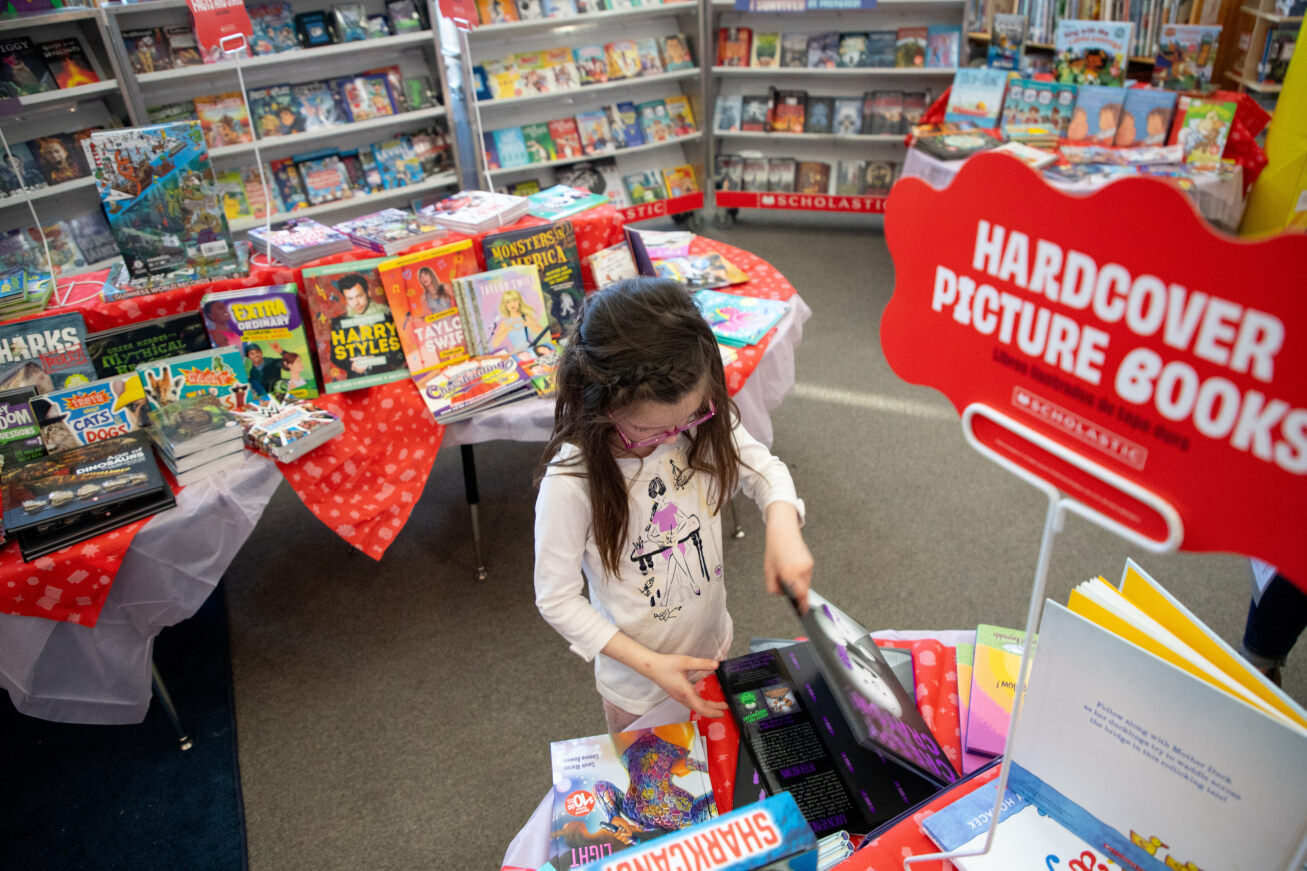 A little girl browses the Scholastic Book Fair