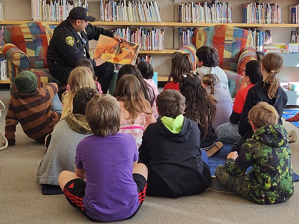 Officer Rodriguez in uniform reading to students.