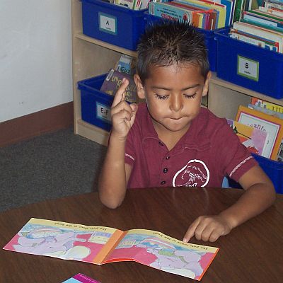 A boy with a book holding up a finger